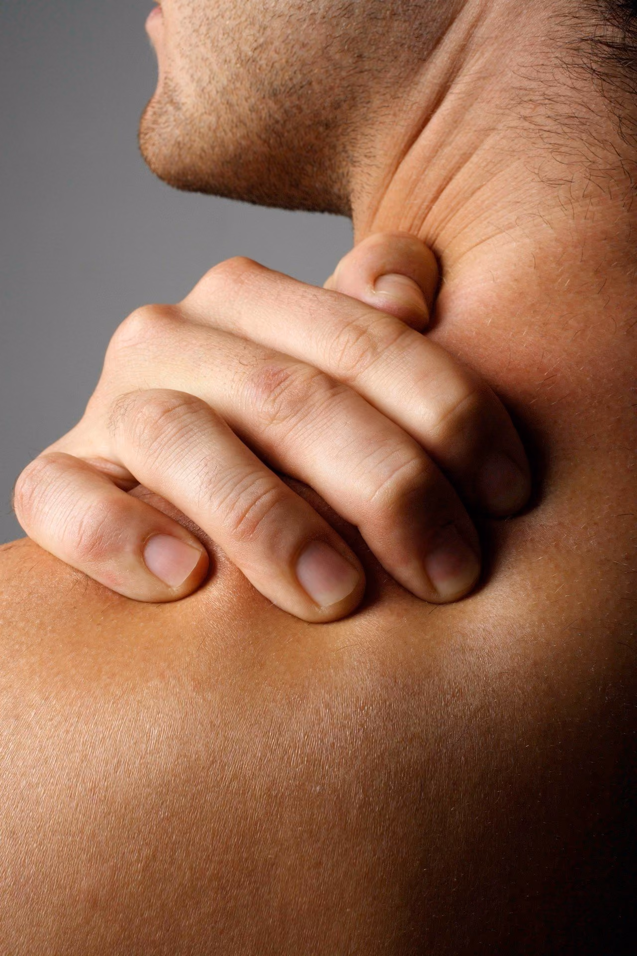A man holding the back of his neck in discomfort