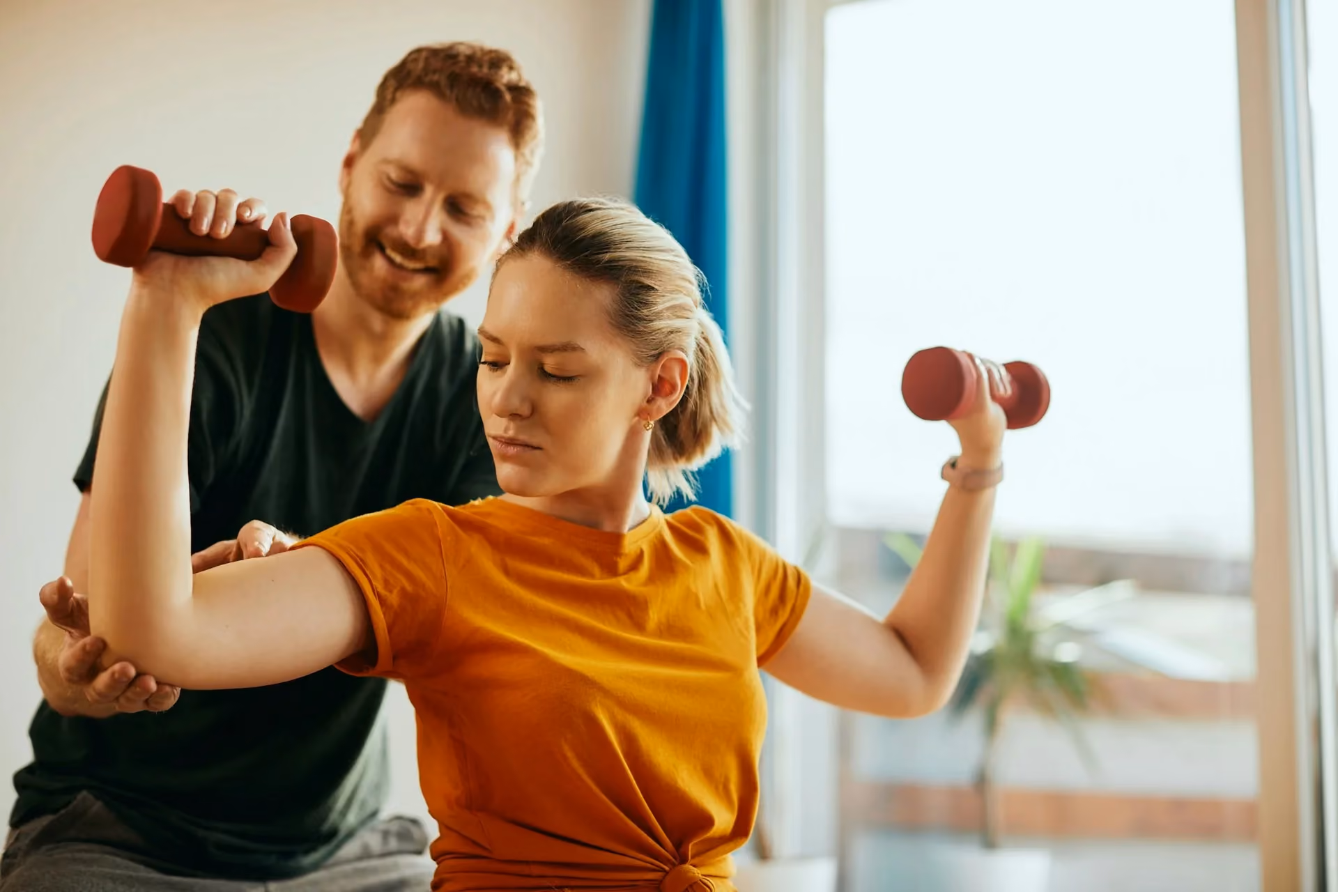 Physiotherapist guiding a patient through a shoulder exercise with dumbbells