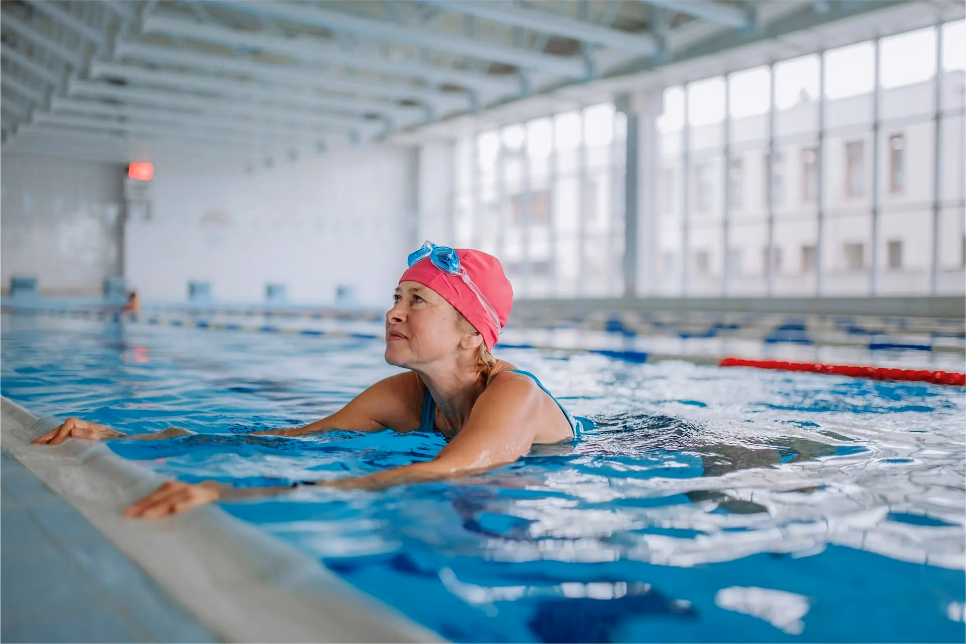 Older woman holding the edge of an indoor pool during a hydrotherapy session