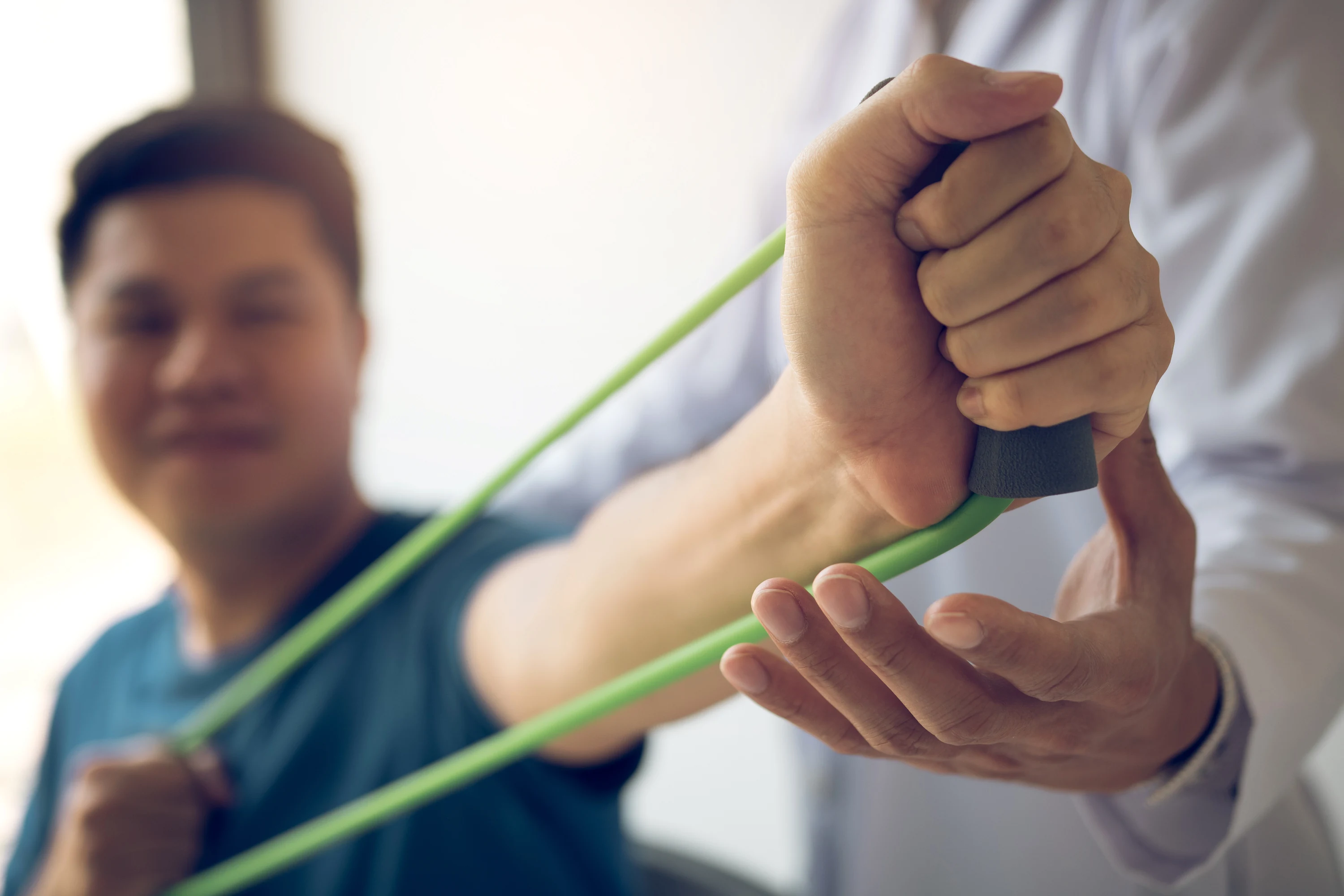 Physiotherapist guiding a patient through a resistance-band arm exercise