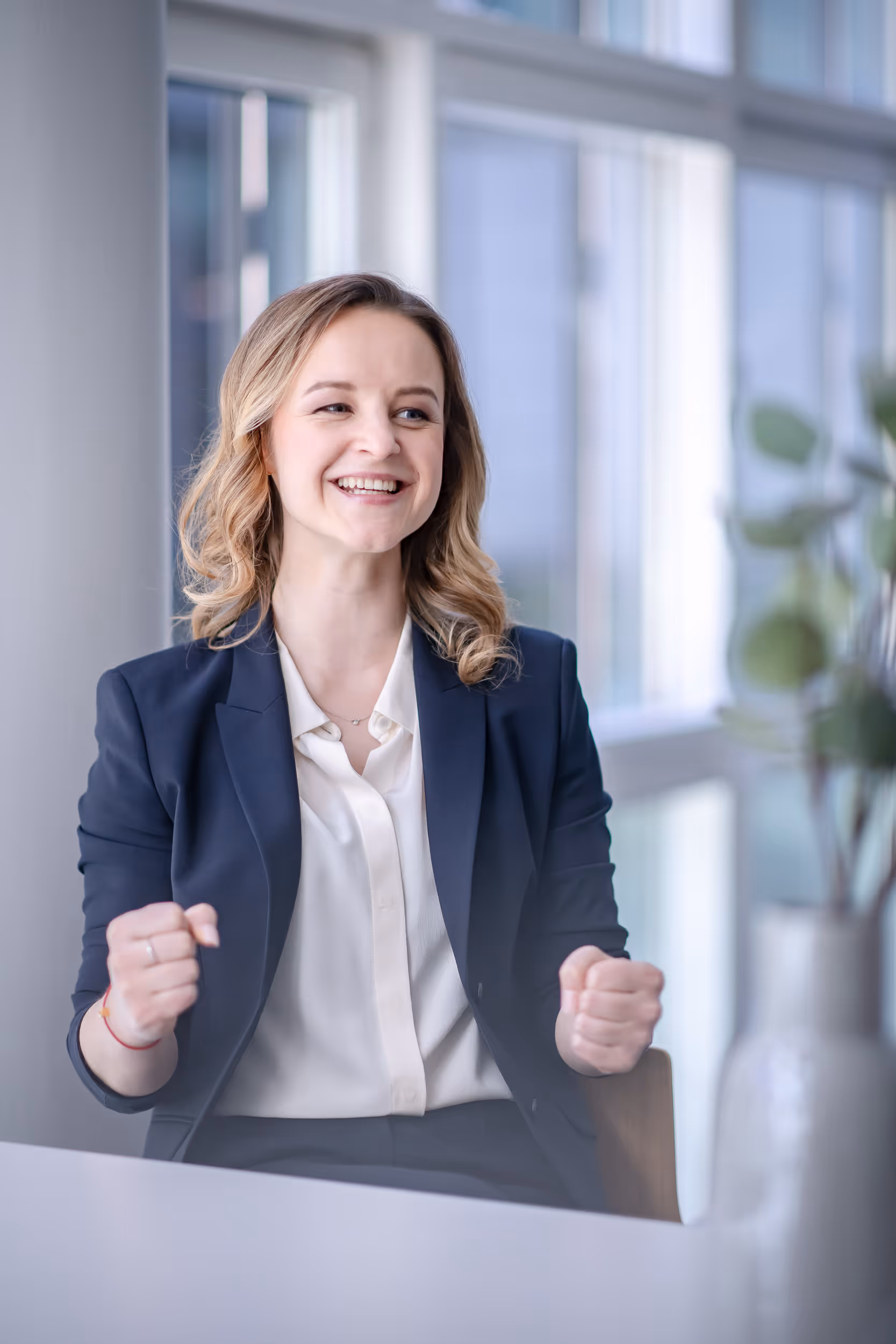 Trainerin Anna Rivna lächelt euphorisch, ballt beide Fäuste und zeigt Begeisterung – symbolisiert, wie sie Teilnehmende mit Kompetenz und Empathie mitreißt in Coaching, Training und Weiterentwicklung für Unternehmen, Mitarbeitende und Einzelpersonen.