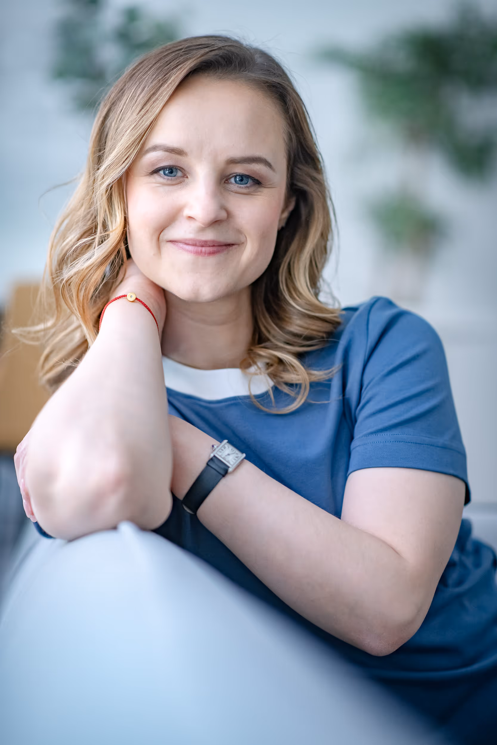 Trainerin Dr. Anna Rivna sitzt lächelnd auf einer Couch – symbolisiert Empathie und Wissenskompetenz in Coaching, Training und Weiterentwicklung für Unternehmen, Mitarbeitende und Einzelpersonen in Workshops.