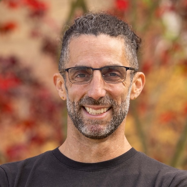 Mike Pesavento headshot, smiling with bokeh red/gold leaves in background