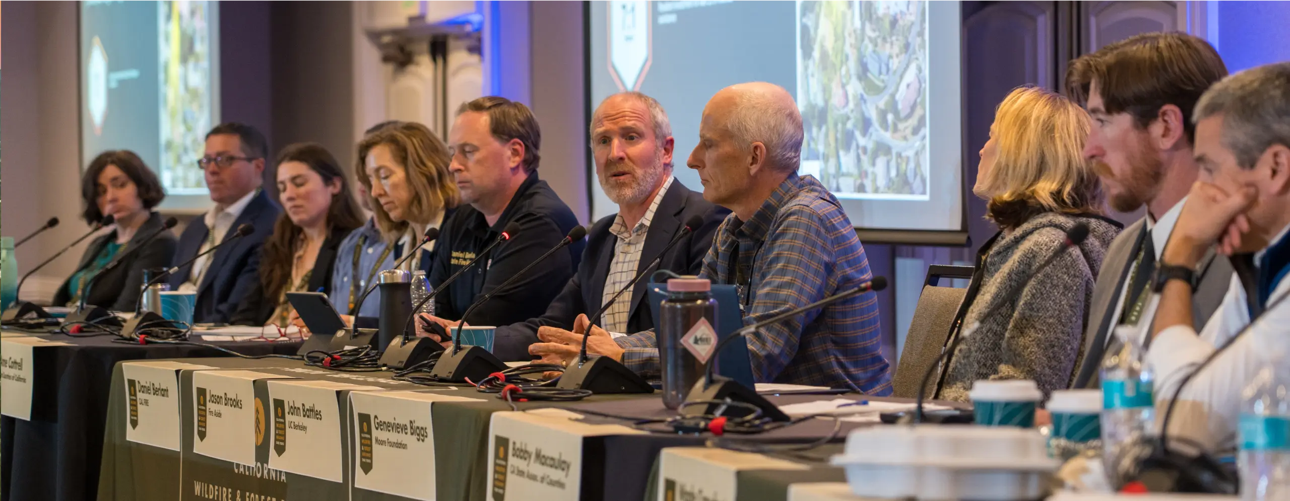 A group of people sitting at a table with microphones.