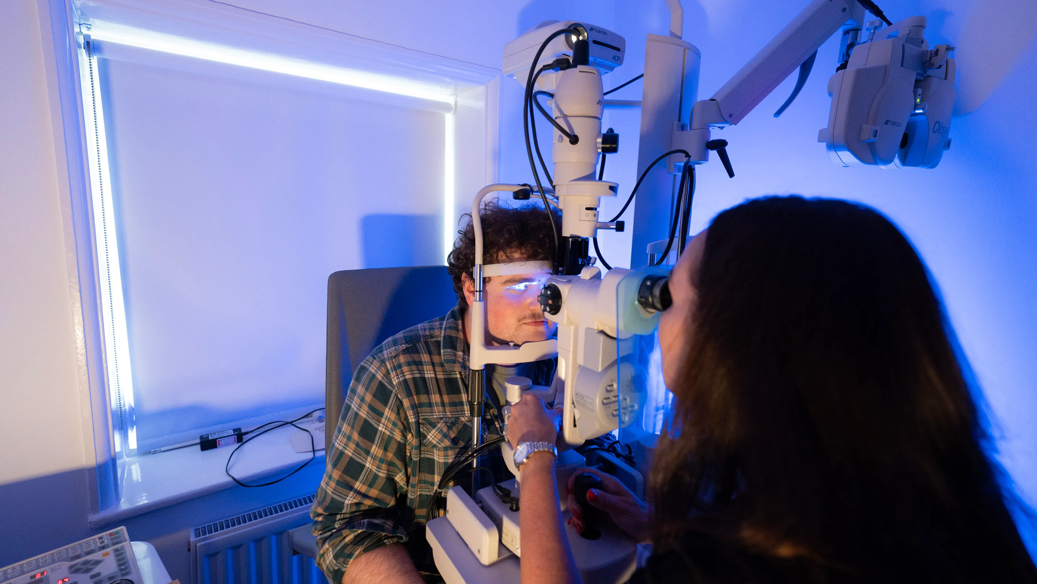 Eye exam with advanced optical equipment in blue-lit medical room
