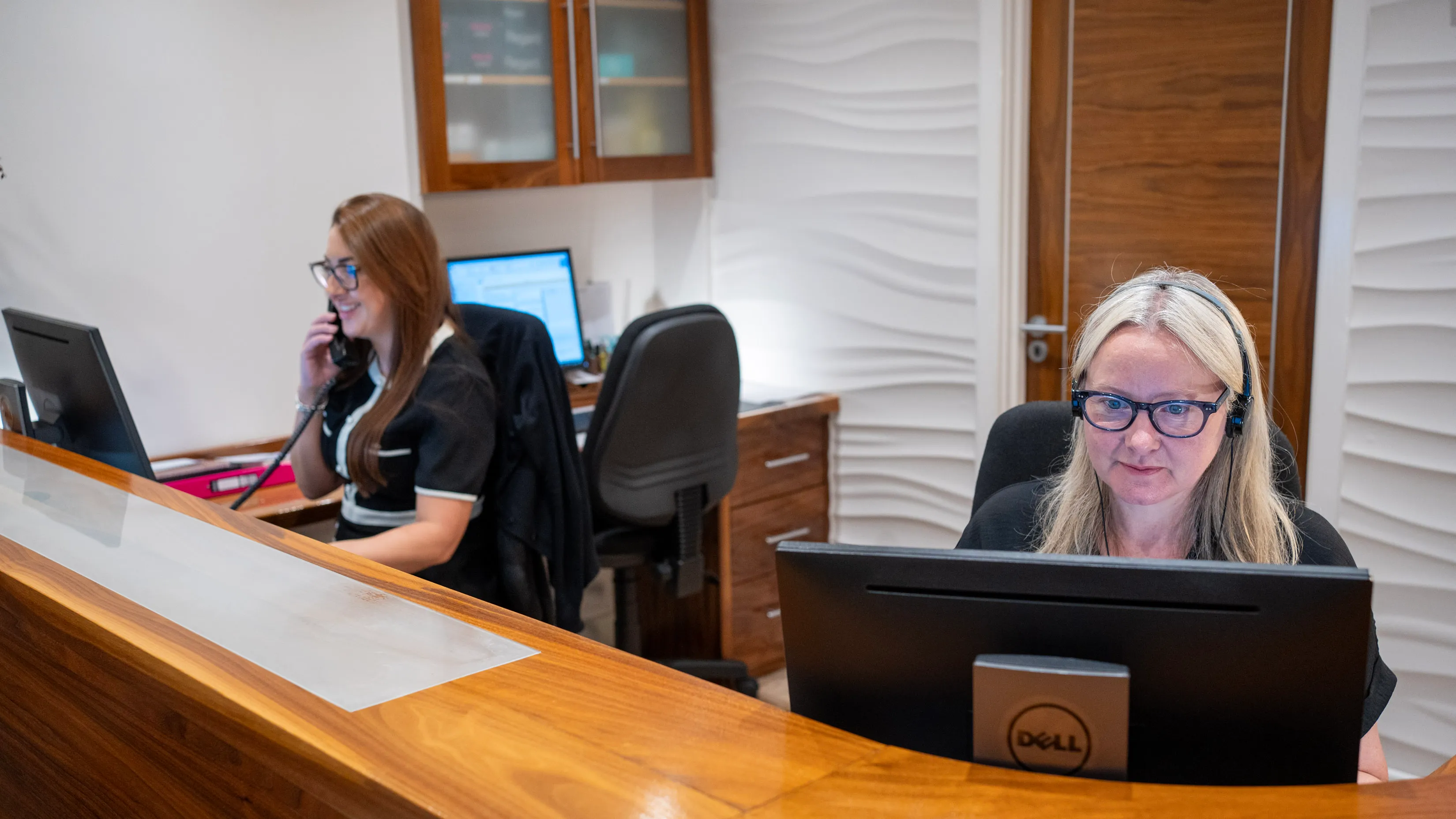 Two women working at desks with computers in modern office
