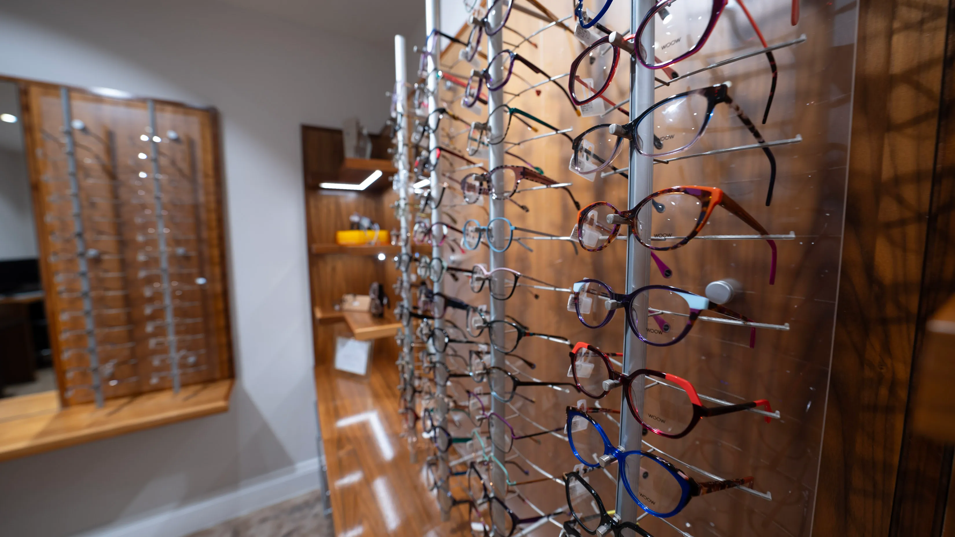 Colorful eyeglasses displayed on metal rack in optical store showroom