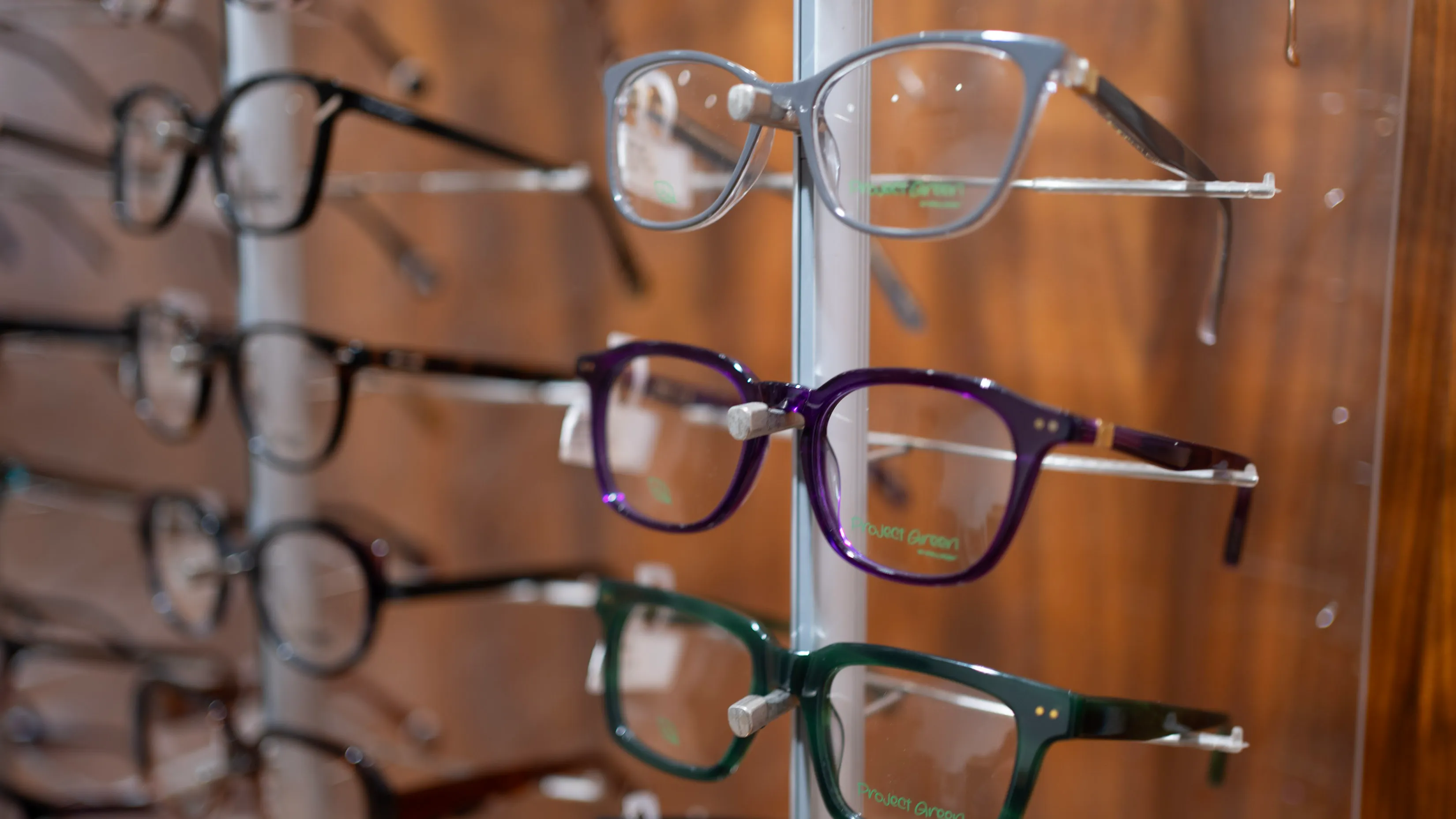 Colorful eyeglasses displayed on a vertical stand in an optical store