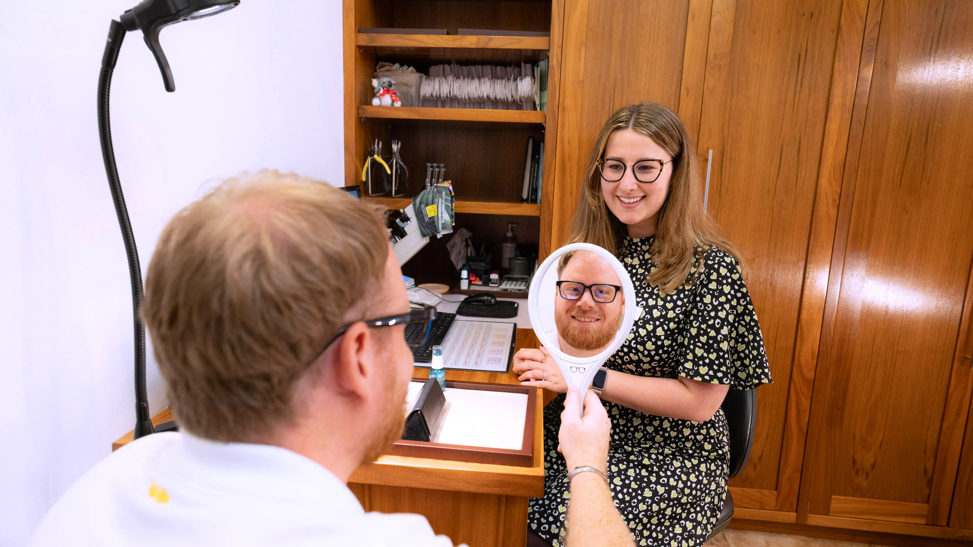 Smiling researcher looks through magnifying mirror in scientific workspace