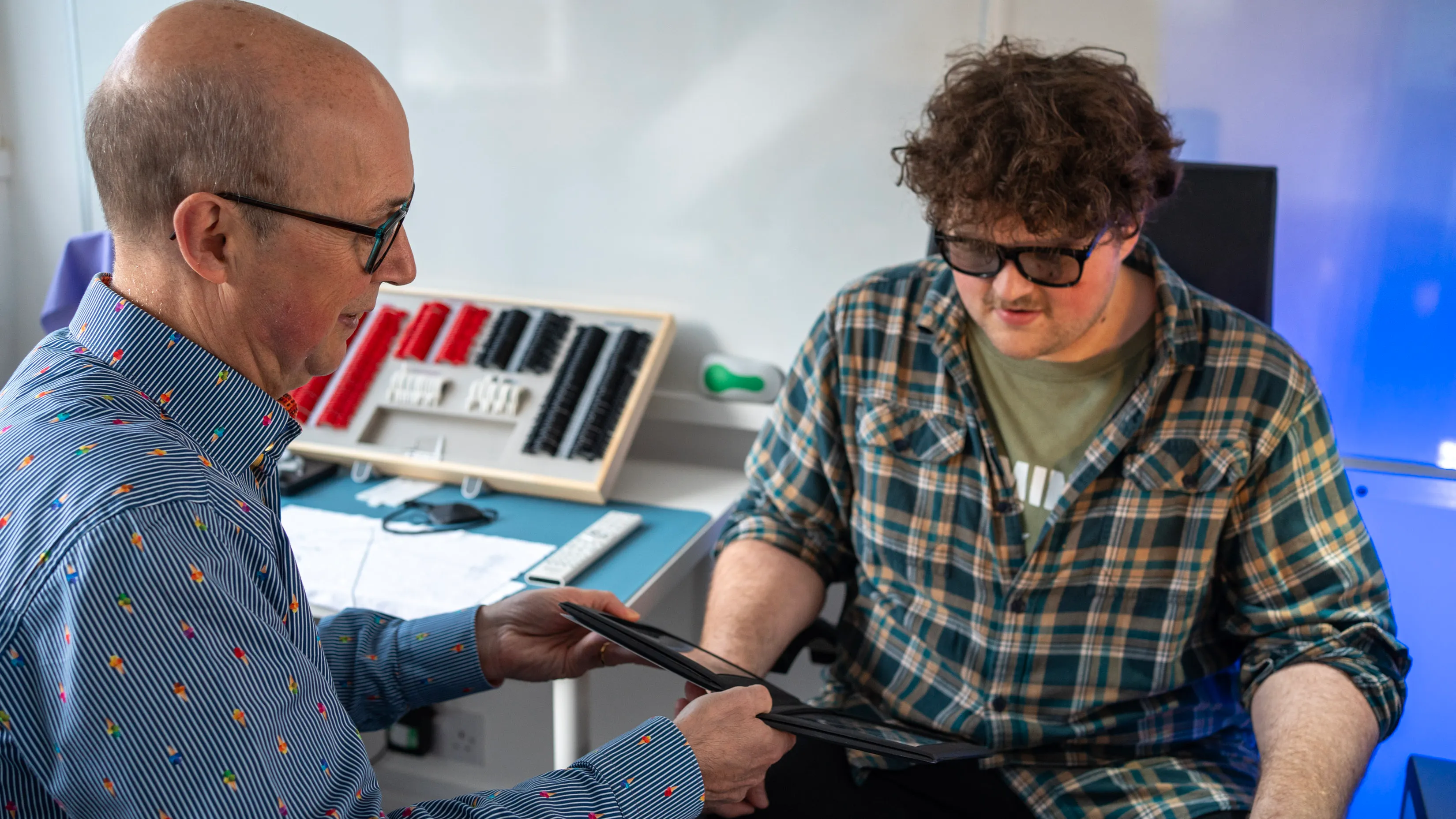 Two men collaborate in office, reviewing documents with color swatch board
