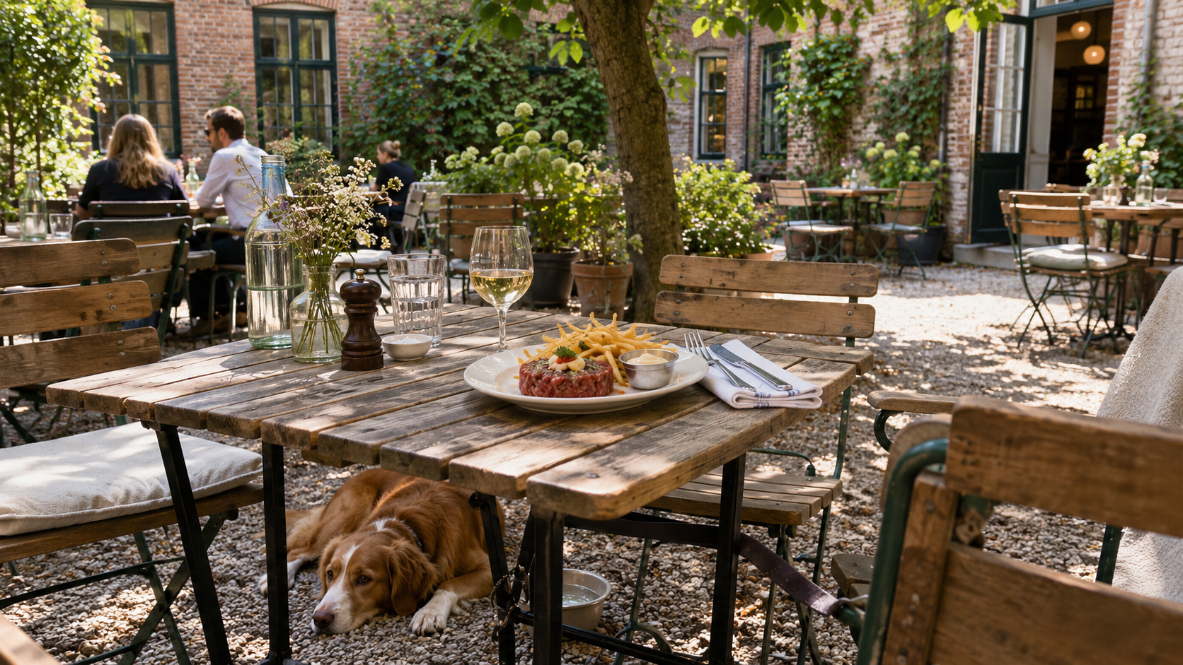 A dog resting beneath a table on a sheltered courtyard restaurant terrace in Copenhagen