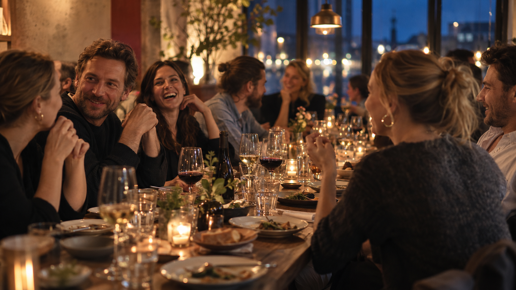 A long communal table set for a group dinner in a Copenhagen restaurant, warm evening light