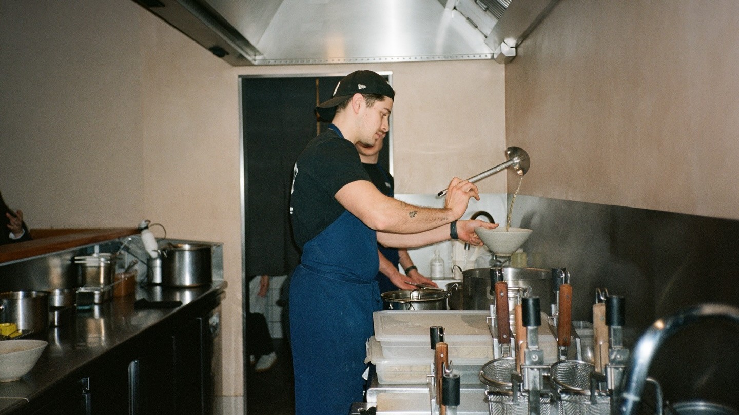 A cook ladling broth into a bowl at the Slurp Borgergade kitchen pass