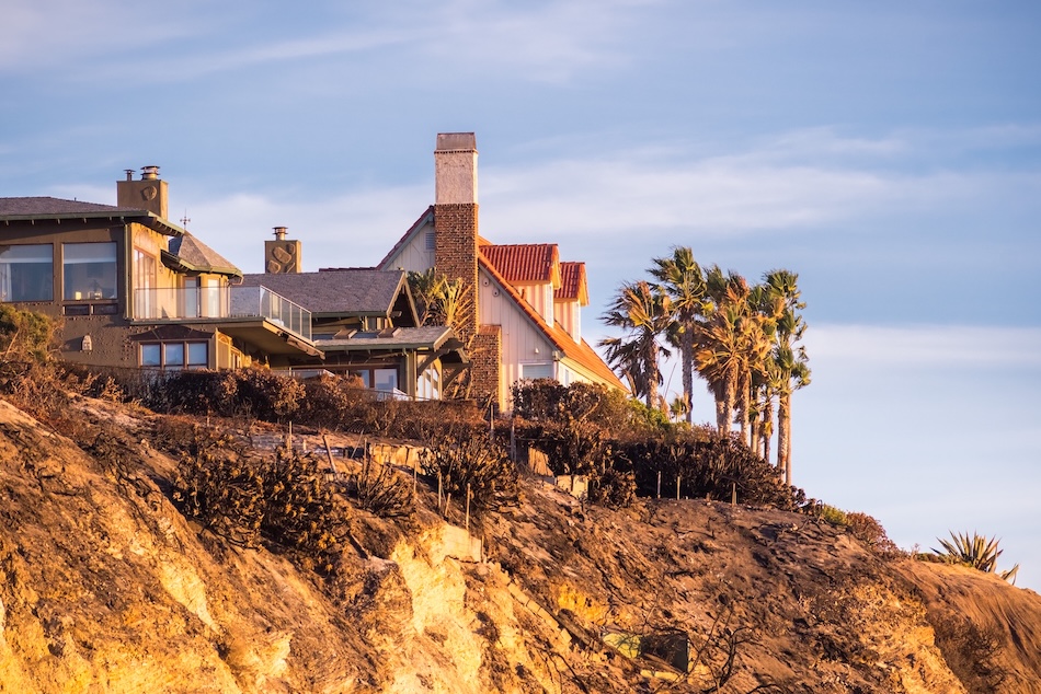 Coastal California homes on a cliff at sunset with palm trees and ocean views.