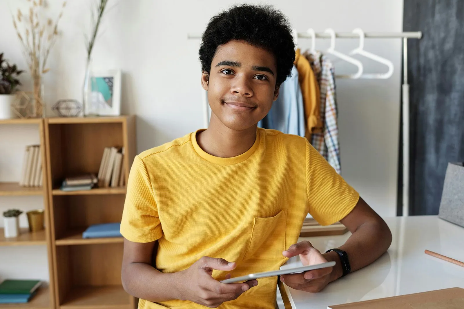 A student wearing a yellow t-shirt sits with a calm expression