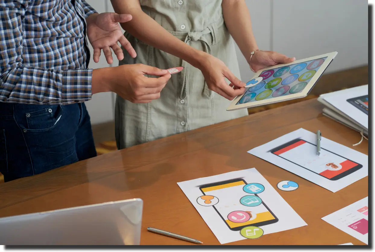 Unrecognizable colleagues looking at tablet and trying different icons.