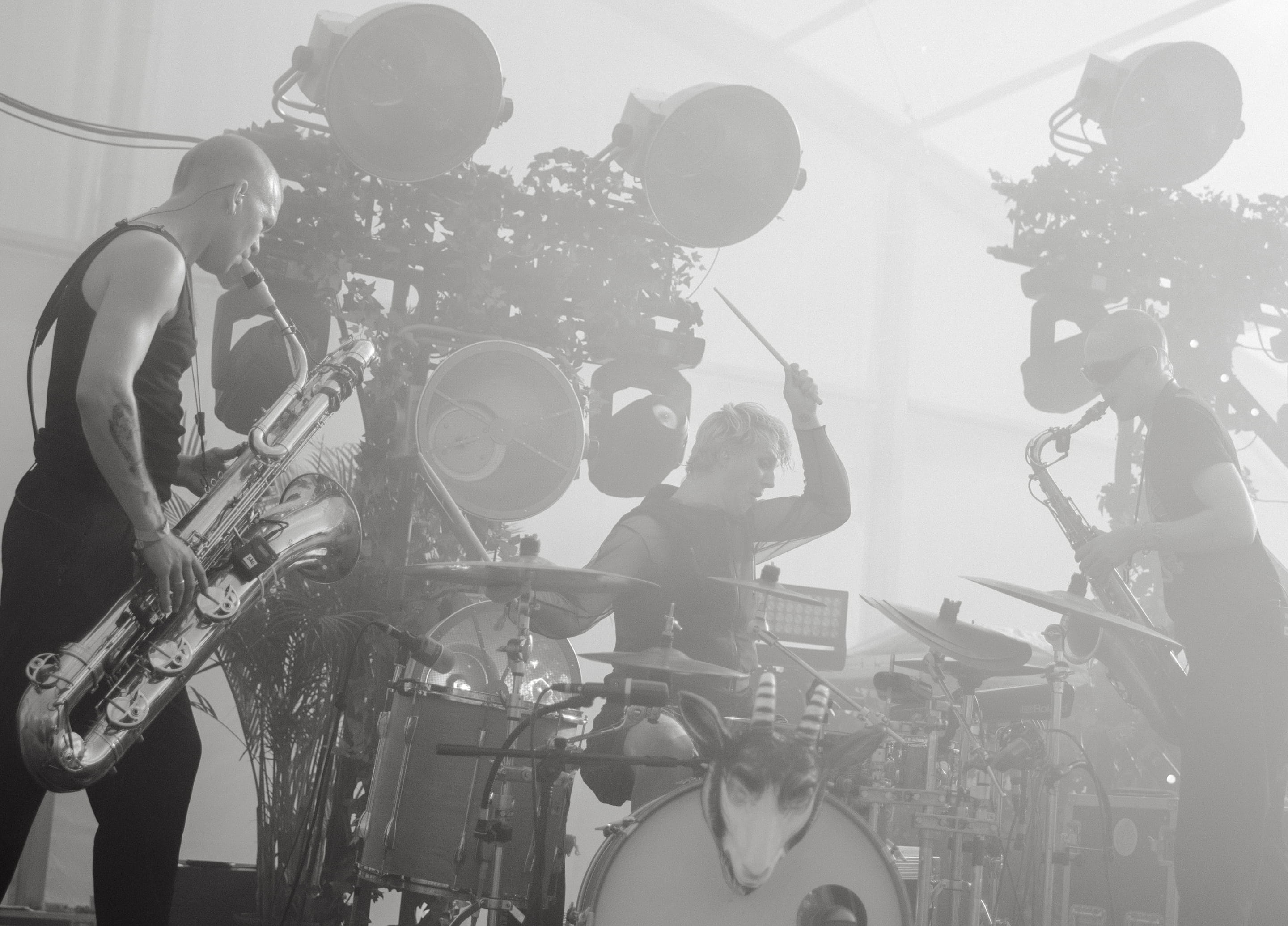 The band Smag På Dig Selv performing live at O Days at the Orangerie stage, with energetic drumming and saxophone under moody stage lighting.