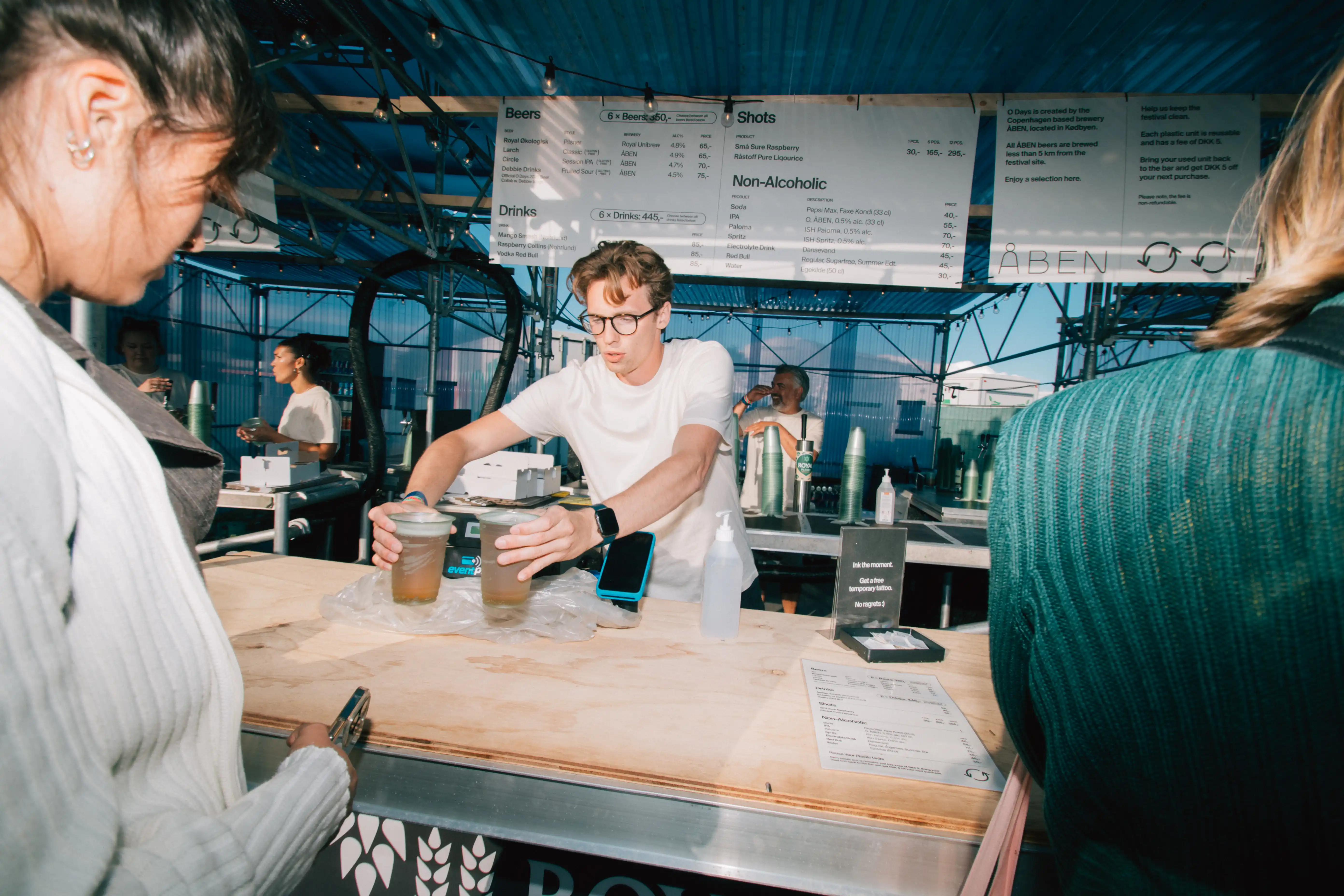 O Days volunteer in the bar delivering beverages to a festival goer.