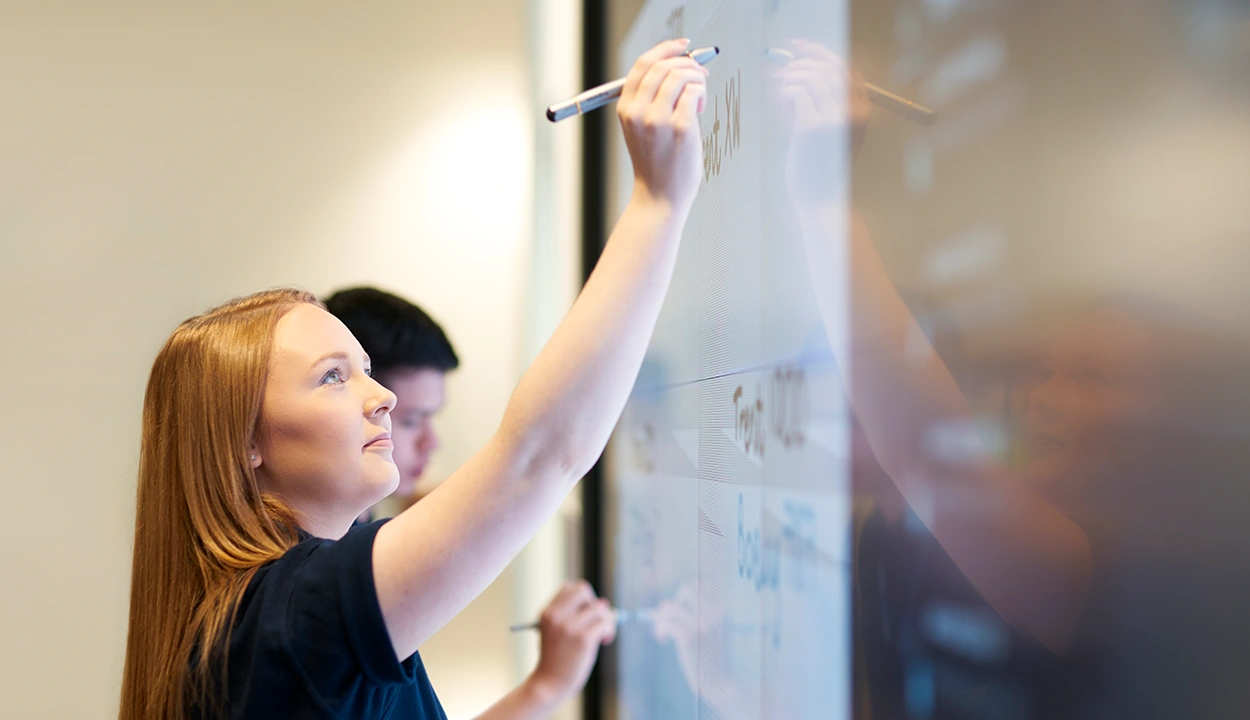 Female worker writing on an interactive whiteboard in an office