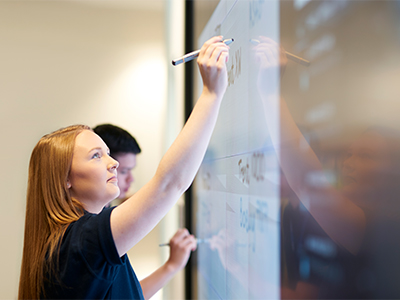 Female worker writing on an interactive whiteboard in an office