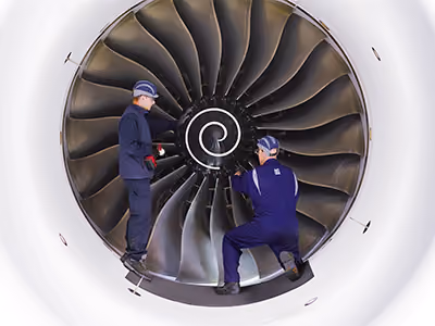 Two engineers working together on an aeroplane jet engine