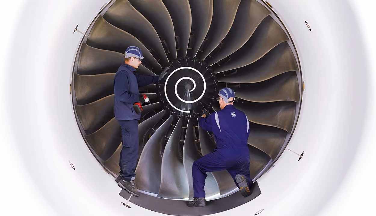 Two engineers working together on an aeroplane jet engine