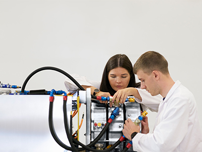 Two engineers working on an engine in a bright workshop
