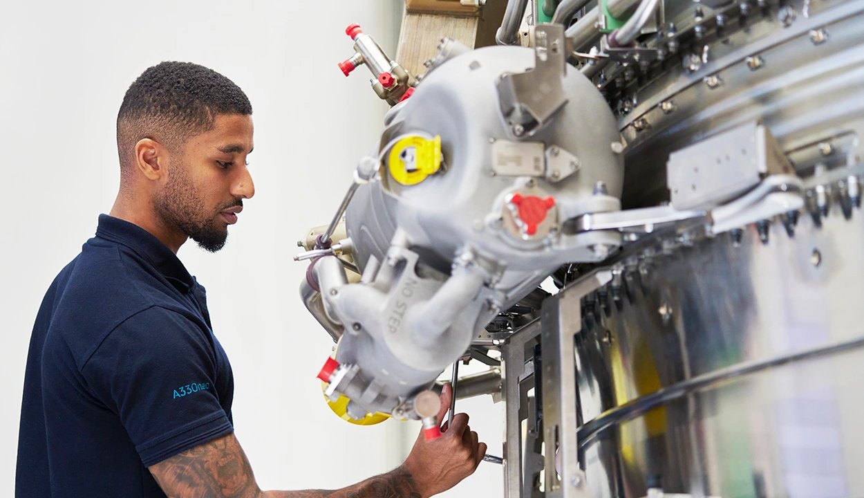 Male engineer working on an engine in a bright workshop