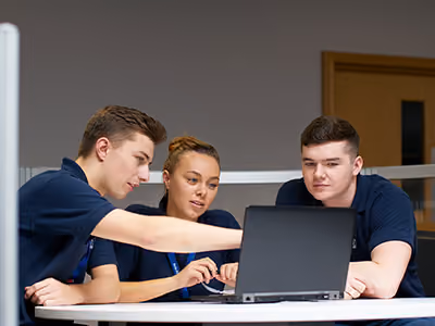 Three co-workers talking through information on a laptop