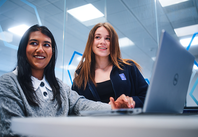 Two female co-workers collaborating on a laptop