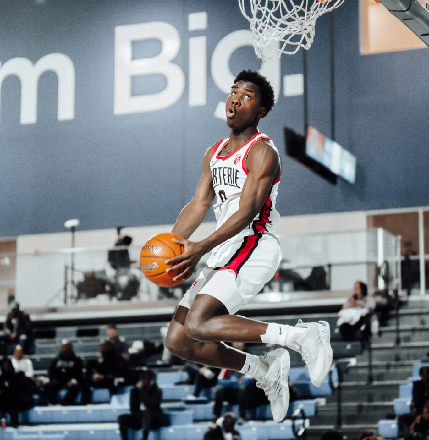 Basketball player jumps in the air, holding the ball, about to make a slam dunk.