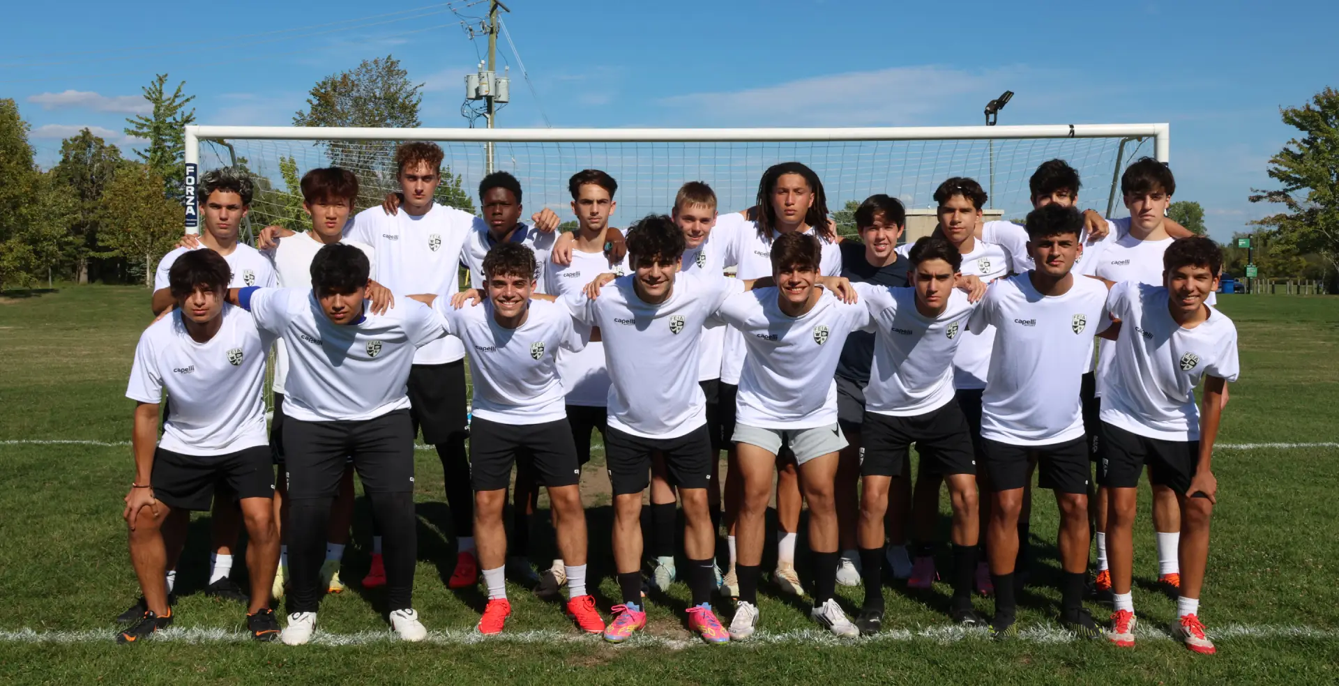 A group of young men in soccer uniforms pose together in front of a goalpost.