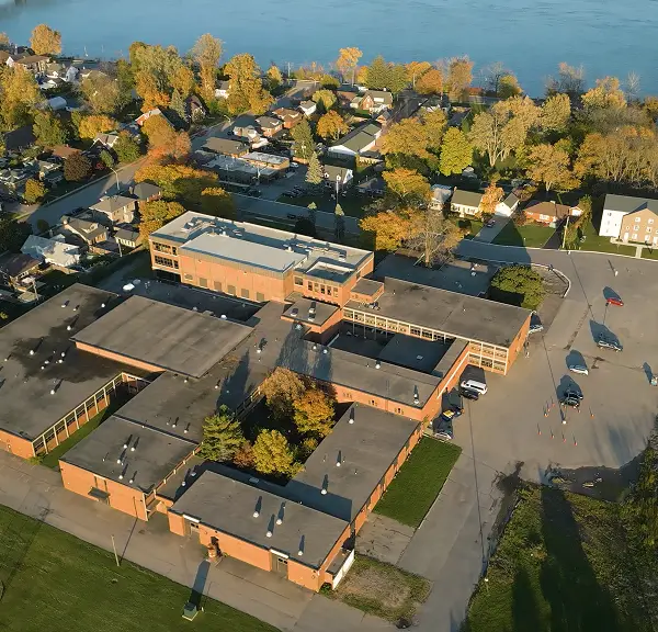 Aerial view of a school building surrounded by residential houses and trees in autumn.