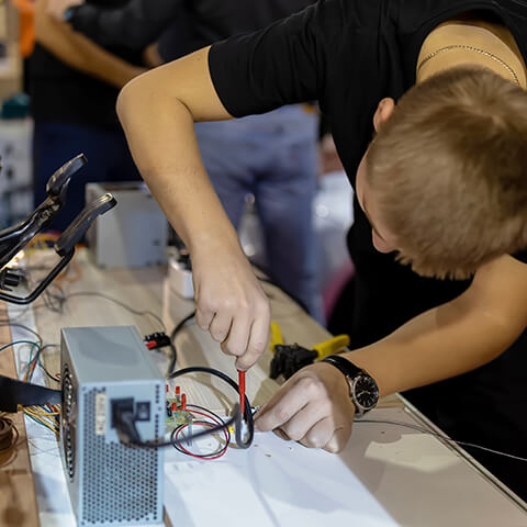 Student wiring an electronic circuit to a power supply at a workbench