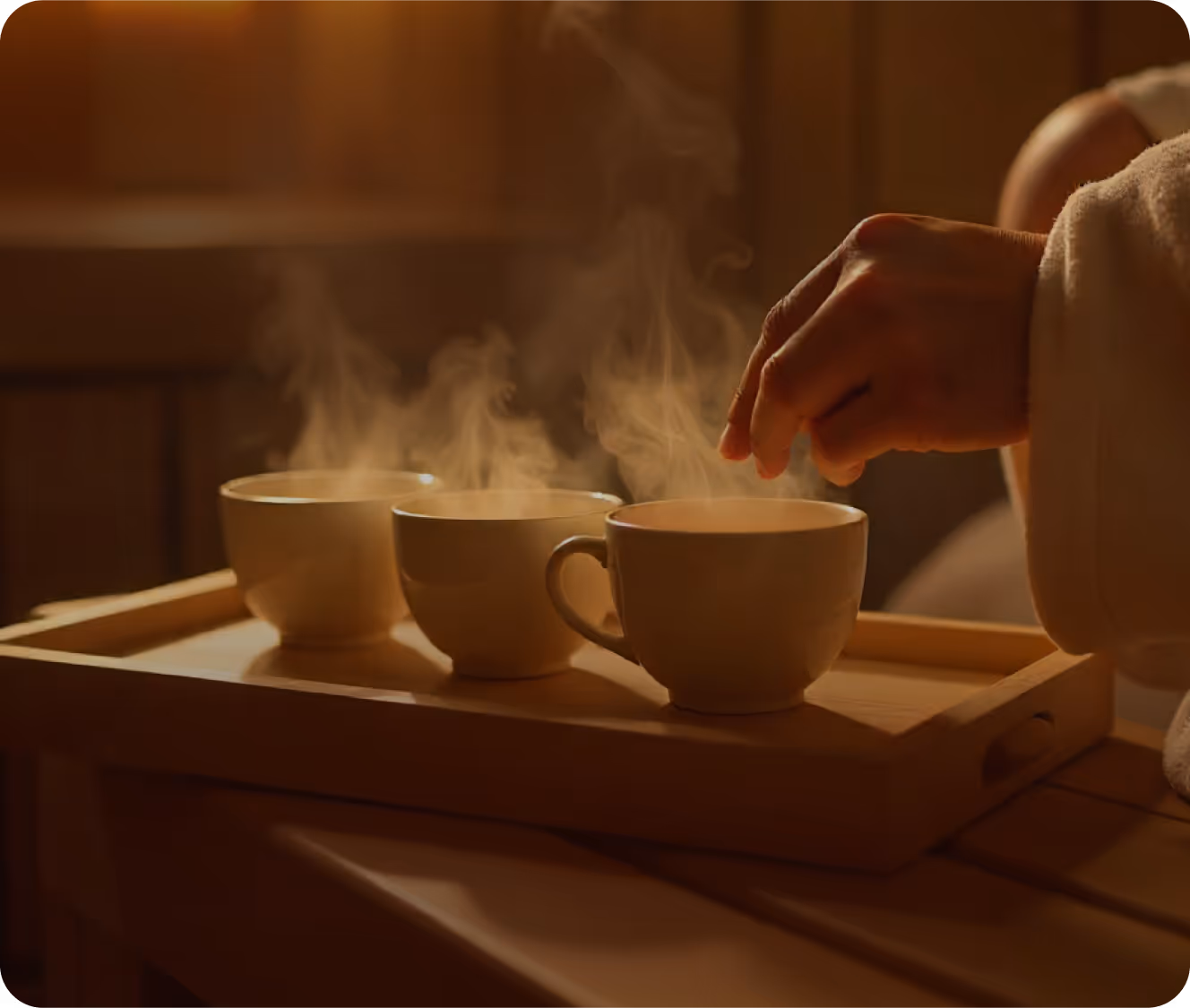 Steam rising from cups of herbal tea on a wooden tray, featured in the Tea Ceremony Sauna at the Toronto Sauna Festival