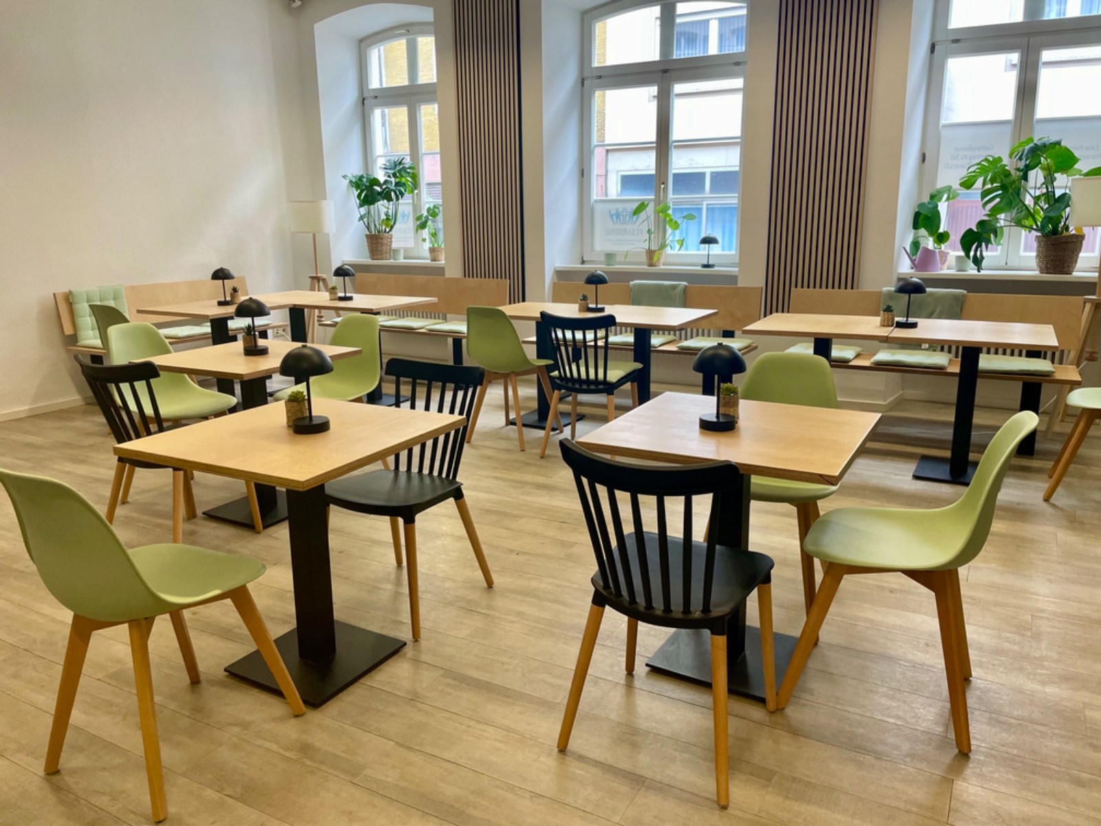 Heller Raum mit Fenstern, Tischen und Stuehlen