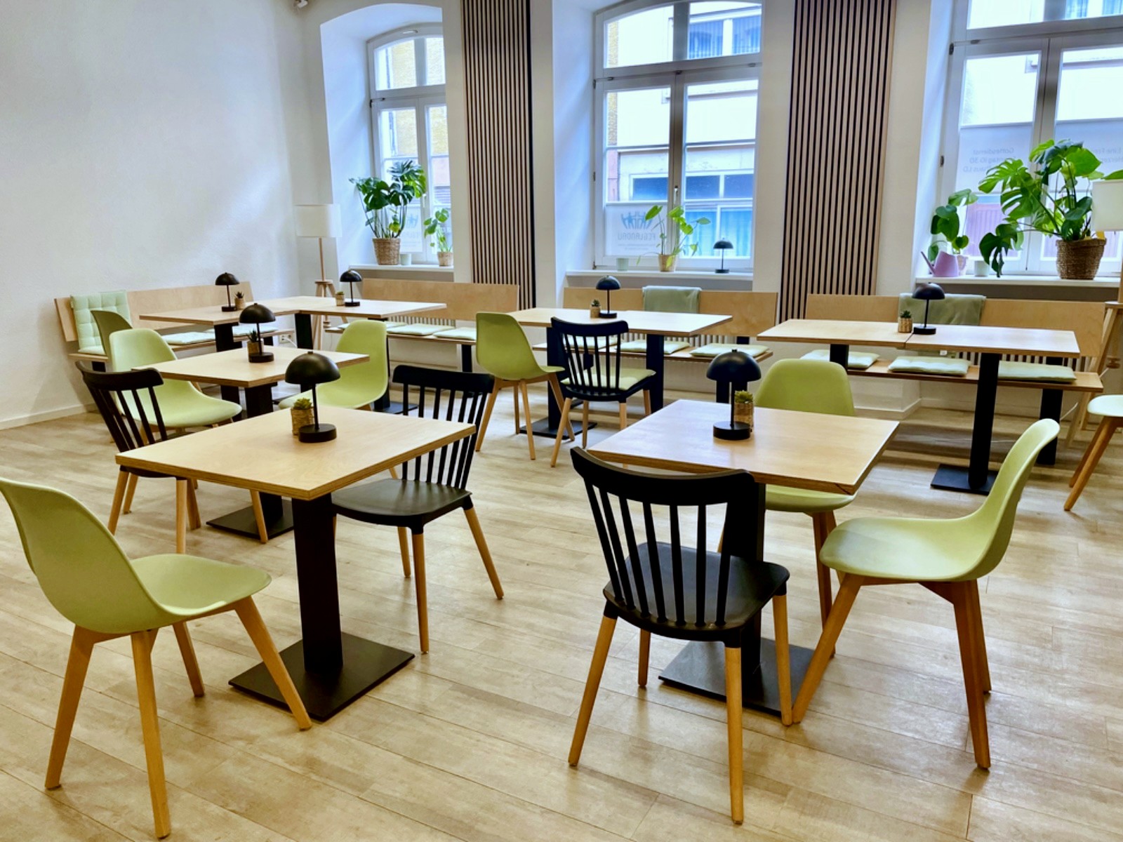 Heller Raum mit Fenstern, Tischen und Stuehlen