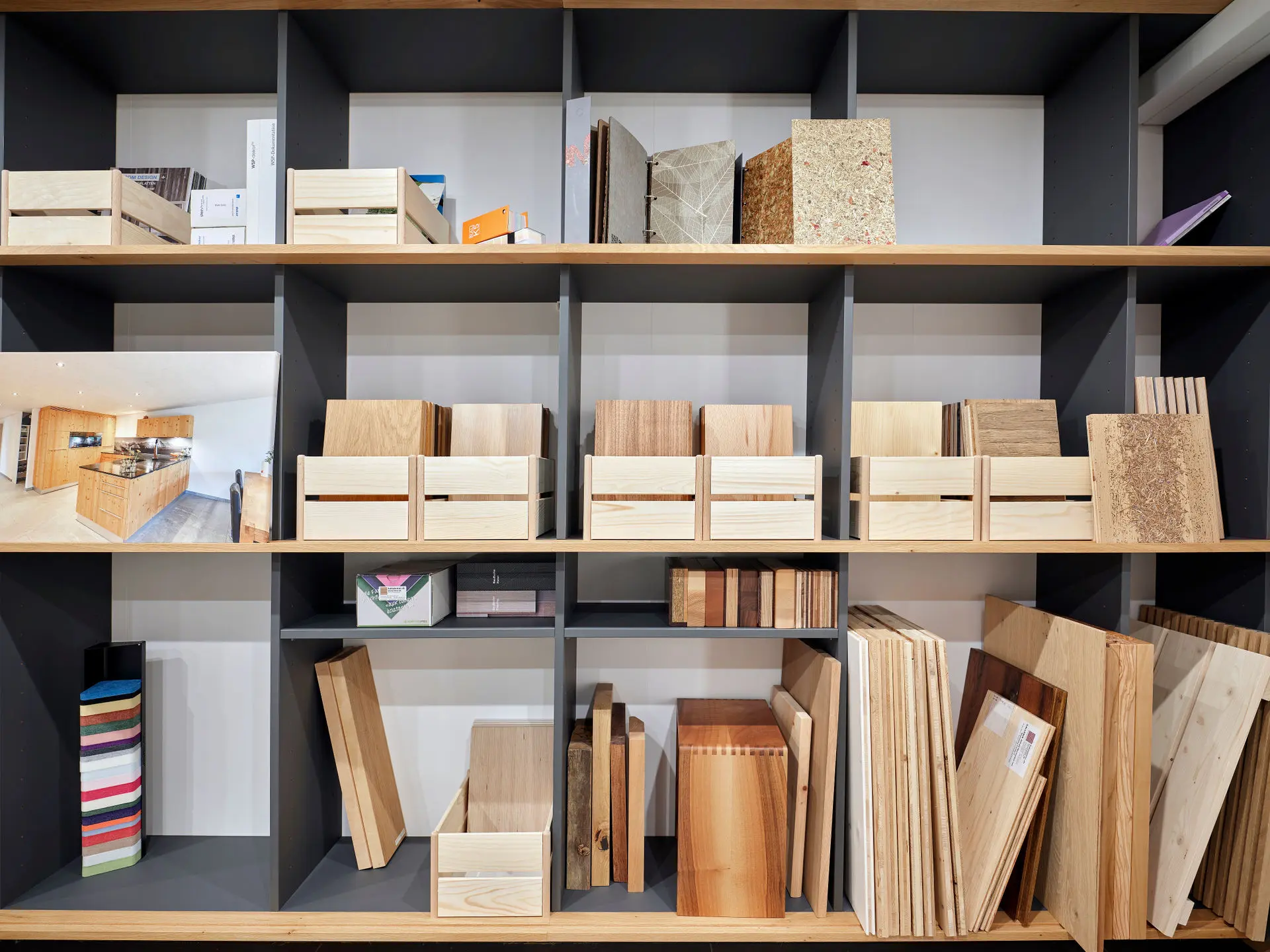 Regal mit verschiedenen Holzmustern und Materialien, darunter Holzplatten, Holzkisten und Farbmuster.