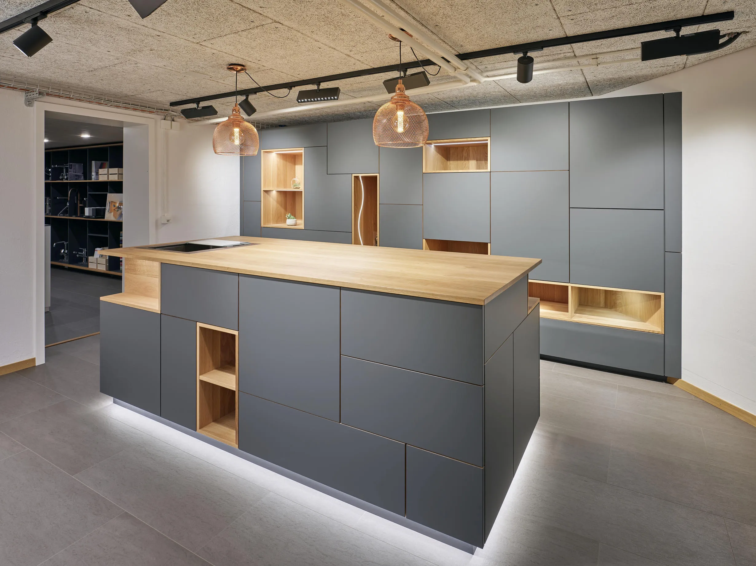 Moderne Küche mit grauen Schränken, Holzarbeitsplatte auf Kochinsel und eingebauten Holzregalen.