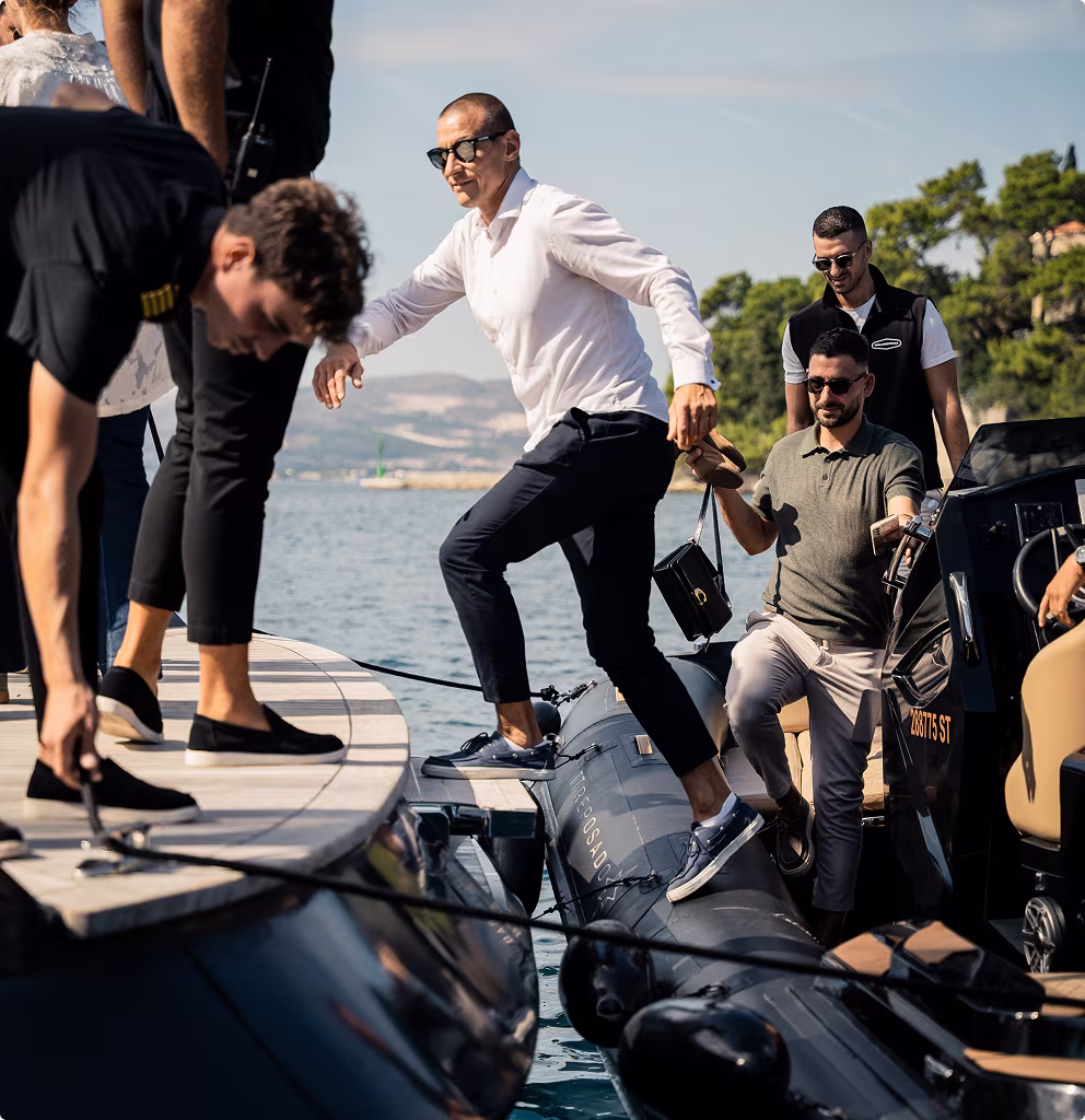 Men in sunglasses boarding a boat from a dock on a sunny day.