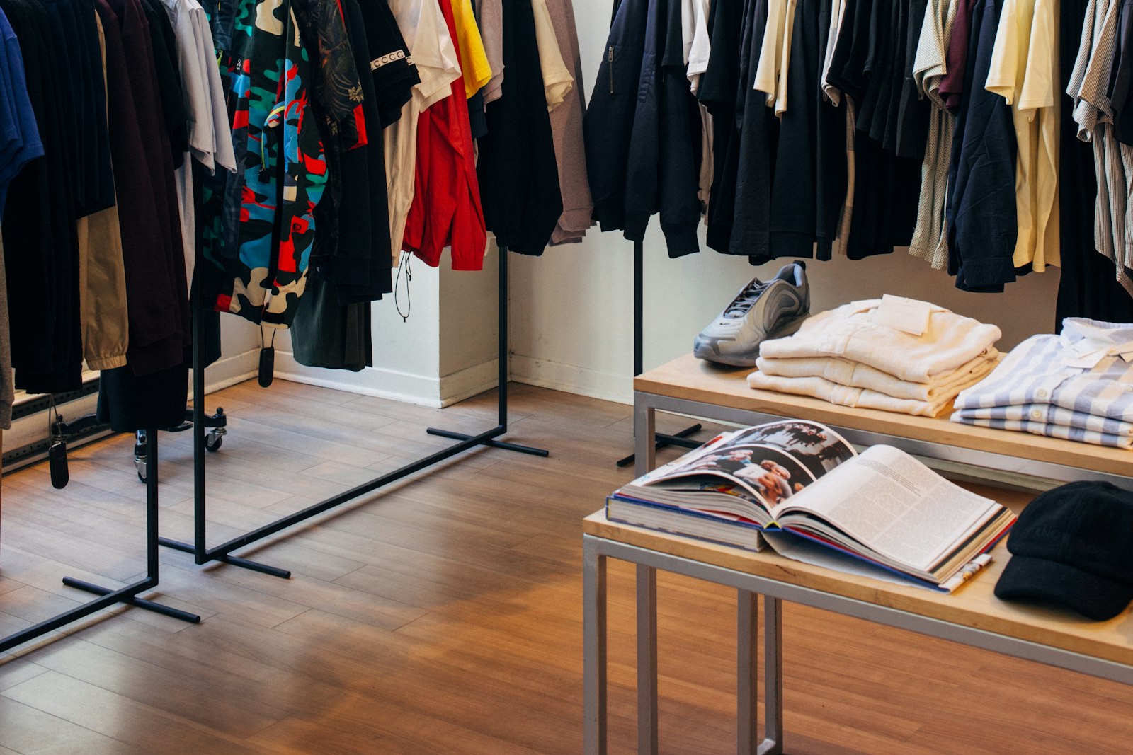 Burros de ropa y mesa con prendas dobladas en una tienda de moda
