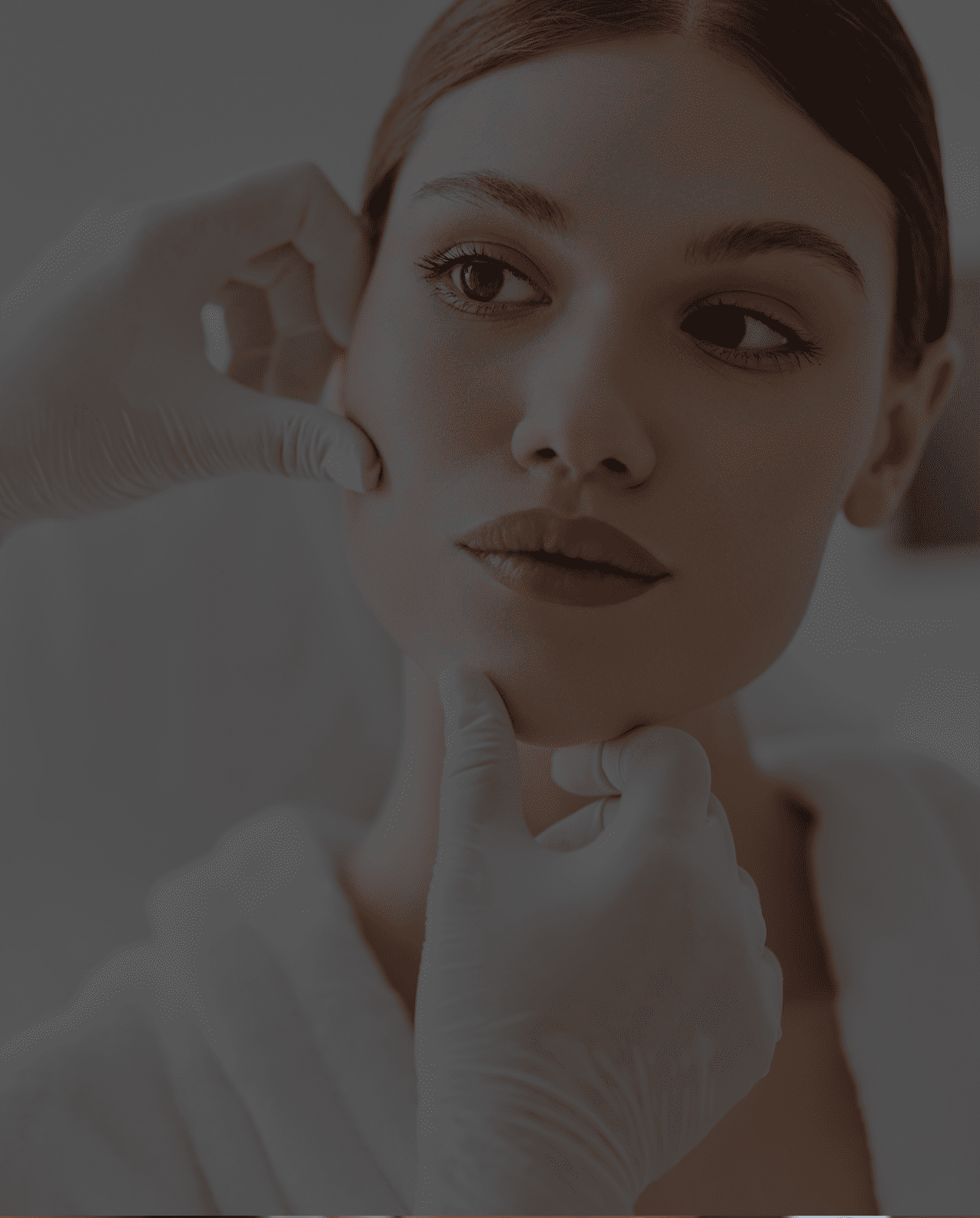 Close-up of a woman receiving a facial examination by a gloved professional.