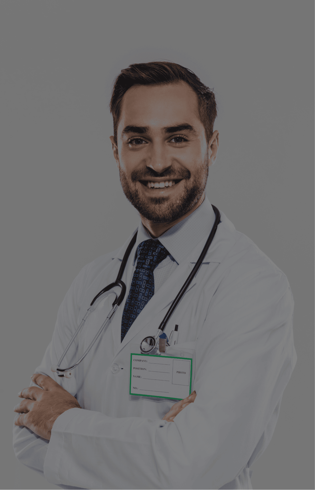 Smiling male doctor with stethoscope around neck wearing a white coat and a blue patterned tie.