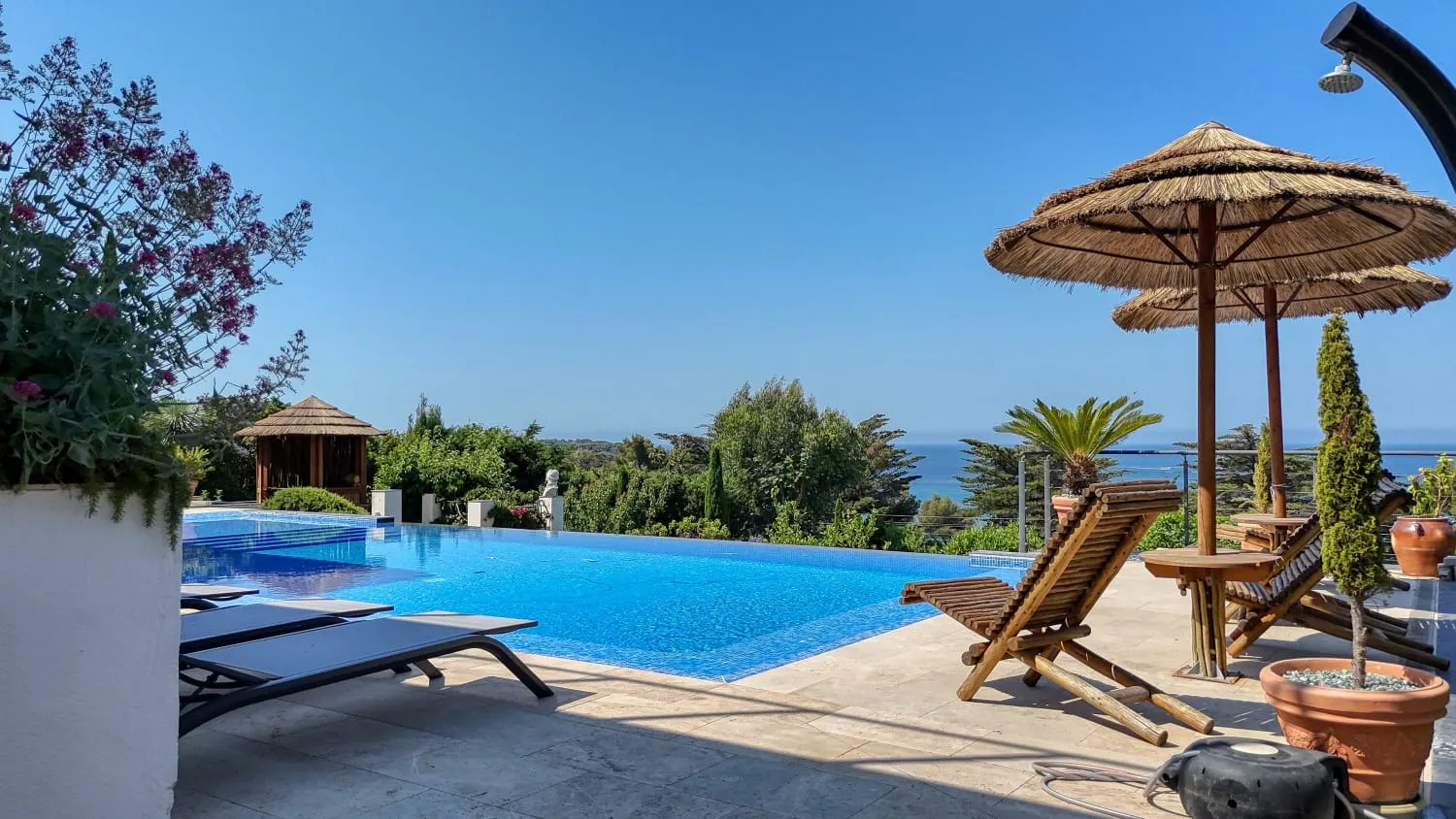 Piscine à débordement vue mer avec transats.