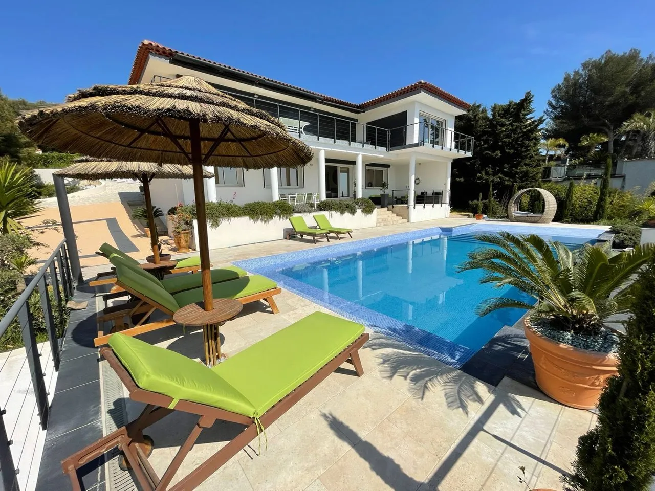 Piscine à débordement avec paillottes et transats autour. Idéal pour se reposer et profiter de la vue.