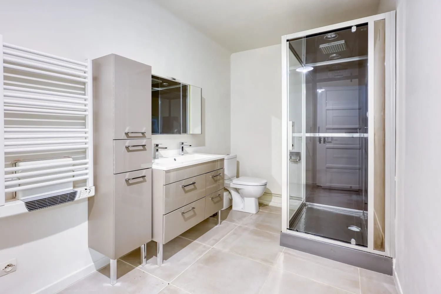 L'une des salles de bain de la villa. Celle-ci est composée de WC, d'une douche, d'un double vasque, d'un sèche serviette et de nombreux rangements.