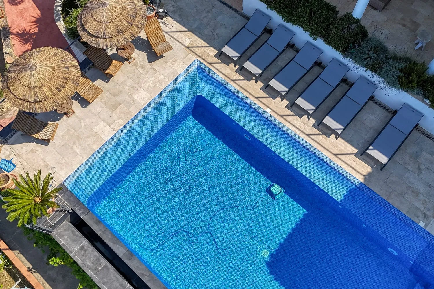 Vue aérienne de la piscine, des transats et des paillottes.