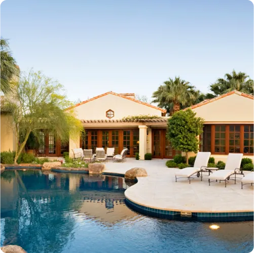 Image of a stucco light colored home next to a concrete pad with a beautifully clean and well maintained pool