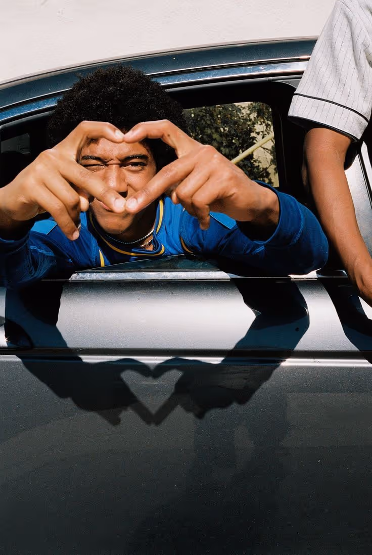 A black kid showing love sign, heart sign with his finger. Charity Mission