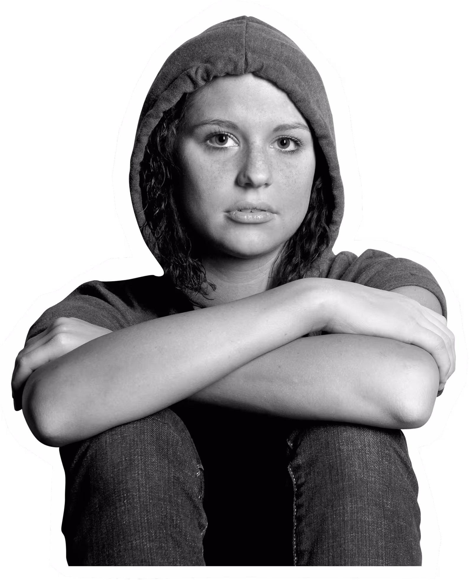 Person in hoodie sitting with arms crossed, looking contemplative in black and white